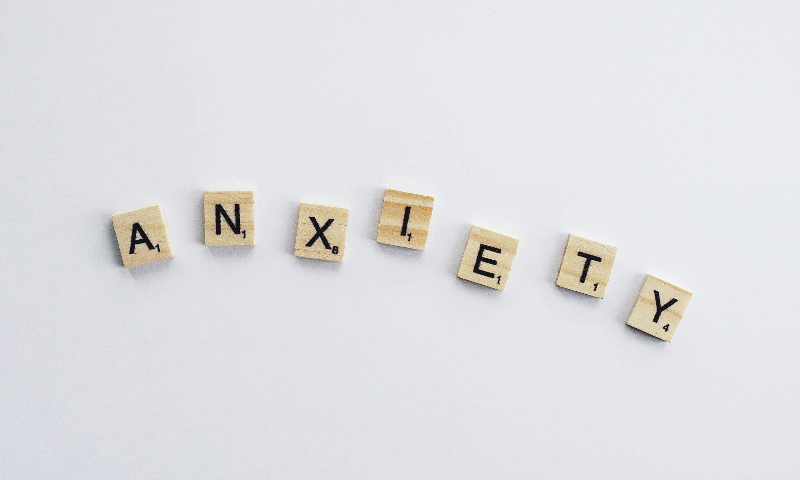 The word 'Anxiety' spelled out using wooden Scrabble tiles on a white background